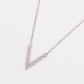 Macro shot of silver V-shaped pendant necklace with sparkling diamonds on thin chain - Steel