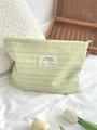 Detailed macro view of striped canvas toiletry bag with textile label and zipper closure - Yellow (Horizontal Stripe)