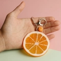 Realistic orange slice PVC keychain with silver metal clasp held in hand on pink background - Large Orange Slice
