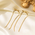 Elegant gold bow earrings with long snake chain tassels on smooth silk background - Bowknot Earrings / Gold