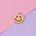 Close-up of golden smiley face hollow pendant on a pink and purple backdrop - Gold