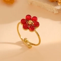 Detail of adjustable gold ring featuring a red cat-eye stone flower on warm background - Gold Red Cat's Eye Ring