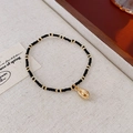 Detail of bohemian beaded necklace with golden conch shell pendant on linen texture - Bracelet-Black-Shell