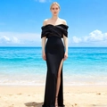 Elegant black off-shoulder evening dress with high slit and satin finish on sunny beach - Black