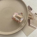 Detail of a square marbled hair claw clip with pink and amber patterns on a ceramic tray - Phantom Purple