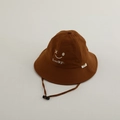 Close-up of caramel sun hat featuring Lucky smiley embroidery and windproof cord - Closed Eyes Smiley / Coffee