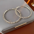 Close-up of silver-plated hoop earrings with sparkling rhinestones on a velvet case - Silver Needle Style