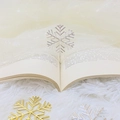 Elegantes marcapáginas de copo de nieve en metal dorado y plateado sobre un libro - Plateado