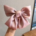 Elegant oversized dusty pink silk satin bow hair clip held by hand for women - Spring Clips / Light Pink