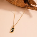 Detail of gold tarot necklace with black enamel Saturn and moon pendant on wood - The World (C120)