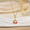 Macro shot of gold cherry pendant necklace with red crystals and green leaves - Gold Red Cherry Green Enamel Leaf