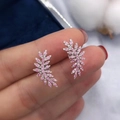 Exquisite leaf-shaped earrings with pink and white zircons held by fingers - Pink