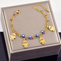 Gold double-layered bracelet with blue evil eyes and Hamsa Hand charms on jewelry box - Hamsa Hand
