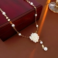 Gedetailleerde close-up van een Franse parelketting met bloemhanger op een donkere tafel - Wit