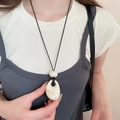 Close-up of a white irregular resin drop pendant on a black cord necklace worn by a model - 61# Necklace-White