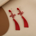 Detail of red Chinese knot tassels and pearl drop earrings on soft fabric background - Red Chinese Knot Tassel