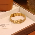 Détail d'un bracelet en maille dorée avec lettre M et cœur dans son écrin - Lettre M