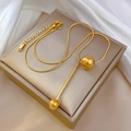 Detail van een gouden kwastjesketting met ronde kralen op een luxe sieradendoosje - Goud