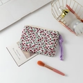 Overhead view of a floral quilted mini makeup bag with golden zipper on a white desk - Red Floral