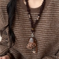 Dettaglio collana con pendente a cuore in peluche leopardato su maglione marrone - Stile pendente a croce