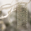 Close-up of golden S-shaped metal Christmas ornament hooks hanging on tree branches - Gold