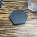 Hexagonal dark grey slate coaster on a rustic wooden table with a glass water cup - Straight Edge Hexagon Style