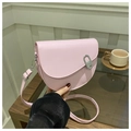 Detailed shot of a pink saddle bag featuring a silver metal oval buckle on a wooden desk - Pink