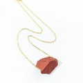 Macro shot of irregular red raw crystal stone pendant on a delicate gold chain necklace - Red Jasper
