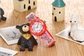 Pink kids watch with cartoon koala pattern and red translucent case near a teddy bear - Dog