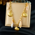 Detailed shot of a gold shell charm bracelet hanging over a silk champagne display box - Gold and Natural Cone Shell Style(N3721)