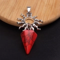 Detalle de un colgante de sol plateado con cristal rojo sobre un plato de madera - Turquesa Roja