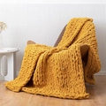 Handmade chunky knit chenille blanket in ginger yellow draped over a wooden chair - 25*100cm / Turmeric
