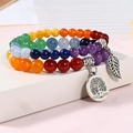 Close-up of tree of life and leaf pendants on multi-color chakra gemstone bracelets - Lotus Multi-color Stones + Antique Silver Leaf