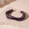 Detail of purple marbled acrylic bangle with irregular wave design on a textured stone - Purple