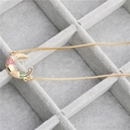 Detailed close-up of a gold crescent moon pendant with colorful zircon on grey velvet box - Colorful Zirconia Moon Necklace