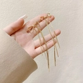 Elegante gouden strik oorbellen met lange kwastjes op een minimalistische achtergrond - Goud