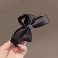 Eleganter Haarklammer mit schwarzer Satinschleife und Kristallmitte am Haar gezeigt - Schwarze Satin-Schleife Haargreifer mit Strass