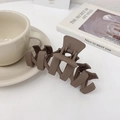 Matte donkerbruine haarklem met golfontwerp gepresenteerd op een minimalistisch magazine - Mat Donkere Koffie