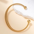 Close-up of golden flexible spring torque necklace with round metal beads on stone - Flexible Spiral Choker Style (Gold#4)