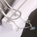 Double-layered silver necklace with blue evil eye pendant and stars on a geometric block - Necklace / Silver