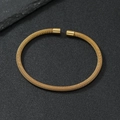 Primer plano detallado del brazalete de acero dorado con textura de malla tejida en espiral - 4mm / Dorado