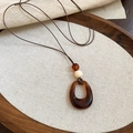 Détail d'un pendentif étoile en résine ambrée avec perle en bois sur cordon ciré marron - Cordon Marron Anneau Rond Ambre