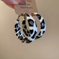 Detail view of large gold-clasp hoop earrings featuring a black and white patterned resin finish - Black and White Leopard Print