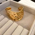 Detailansicht eines breiten goldenen Armreifs mit Hammerschlag-Textur in einer Geschenkbox - Gold (Offen/Gehämmert)