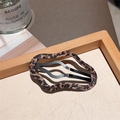 Close-up of wavy leopard print hair clip on a wooden tray with soft natural lighting - Leopard Fabric Wrapped Cloud Clip