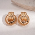 Detail of layered gold mesh circle earrings with woven texture on a stone background - Gold / Gold