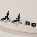 Detailed view of black angel wing earrings with geometric ring on a white pedestal - DNA Double Helix / Black