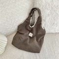 Detail der Cord-Einkaufstasche mit Blumenmuster und Etikett auf weißem Plüschgrund - Braun