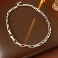 Detailed macro view of a silver link chain necklace on a premium brown leather background - Silver