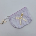 Detalle de estuche lila con volantes que incluye lazo beige y colgante de perla - Morado
